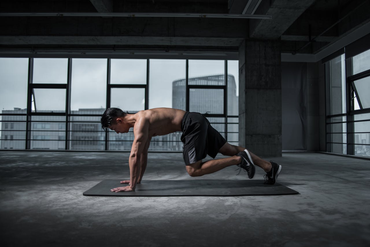 Home Fit man doing mountain climbers exercise inside a modern gym